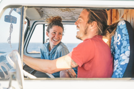 Happy couple inside a vintage minivan making a roadtrip - Travelers driving next to the coast with a van camper - Vacation, love, travel lifestyle conceptの写真素材