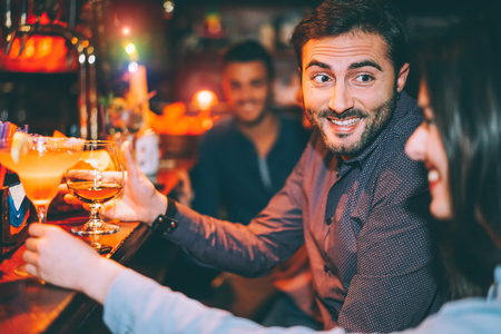 Happy friends having fun at cocktail bar - Young trendy people drinking cocktails and laughing...