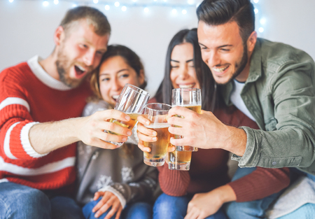 Group of happy friends cheering with beer at christmas party - Young people having fun drinking and...