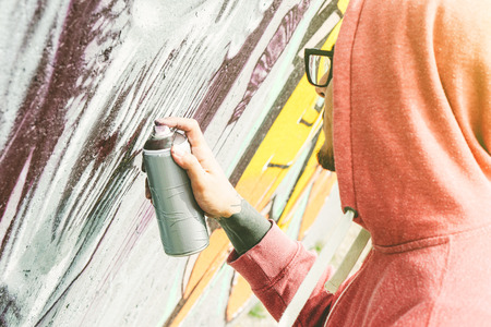 Street artist painting graffiti with color spray his art on the wall  - Young man writing and drawing murales on the street - Urban lifestyle and contemporary art conceptの写真素材