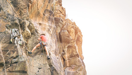 Athletic man clambing a rock wall at sunset - Climber performing on a canyon mountain - Concept of...
