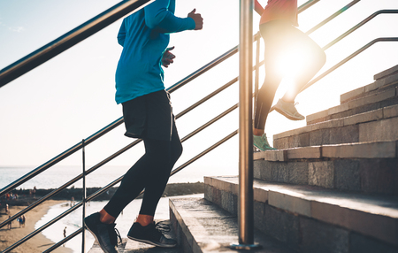 View of runners legs training outdoor - Young couple doing a workout session on stairs next the beach at sunset - Healthy people, jogging and sport lifestyle conceptの写真素材