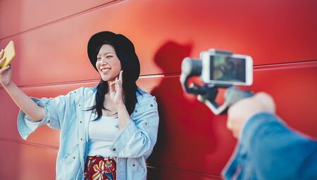 Asian fashion girl vlogging and using mobile smartphone outdoor - Happy trendy Chinese woman having fun making video with gimbal camera - Millennial  generation people lifestyle and technology conceptの写真素材