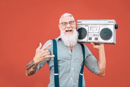 Happy senior man listening to music with boombox outdoor - Crazy hipster male having fun dancing with vintage stereo - Concept of elderly people lifestyleの写真素材