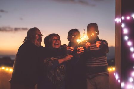 Seniors friends having fun celebrating holidays together outdoor - Happy older people enjoying party laughing on terrace at sunset time - Elderly lifestyle activity and culture event conceptの写真素材