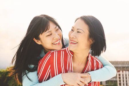 Happy Asian mother and daughter having fun outdoor - Chinese family people spending time together outside - Love, relationship and parenthood lifestyle conceptの写真素材