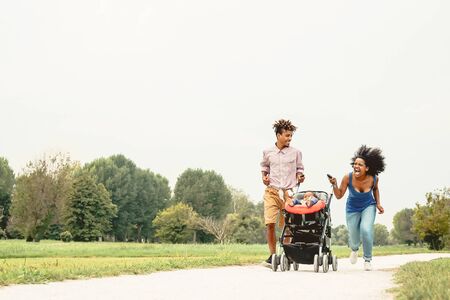 Happy African family having fun together in public park - Black mother father and baby daughter enjoying lovely time outdoor - Happiness, love and parenthood lifestyle conceptの写真素材