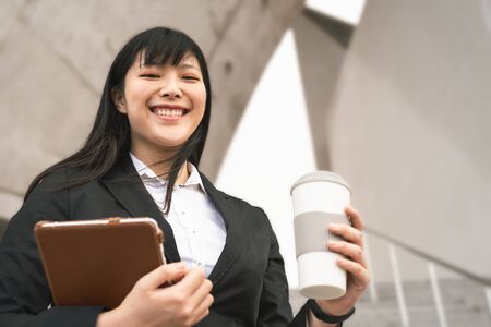Business Asian woman holding laptop and coffee cup outdoor - Young smiling Chinese girl ready for working - Apprenticeship and entrepreneurship job conceptの写真素材