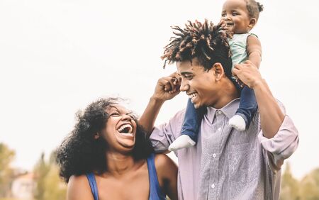 Happy African family having fun in public park - Father mother and little daughter enjoying time and laughing together - Love and parenthood conceptの写真素材