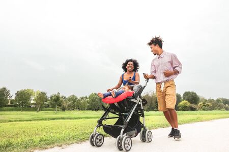Happy African family having fun together in public park - Afro mother and father with their daughter enjoying time together during weekend outdoor - Parents love and mother's day conceptの写真素材