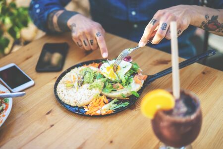Young man eating health food - Tattooed hand guy portrait having brunch in bar restaurant - Healthy...