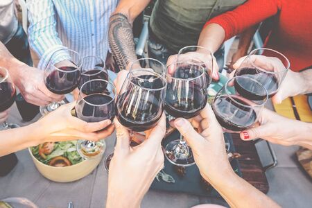 Happy family toasting with red wine glasses at dinner outdoor - People having fun cheering and drinking while dining together - Food and beverage weekend lifestyle activitiesの写真素材
