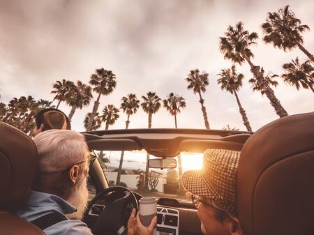 Happy senior couple having fun driving on new convertible car - Mature people enjoying time together...