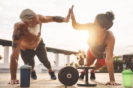 Fitness couple doing push ups exercise outdoor - Happy athletes making workout session at sunset outside - Concept people training and bodybuilding lifestyleの写真素材