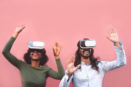 Happy couple using virtual reality headset outdoor - Trendy people having fun with innovated vr googles technology - Tech entertainment and 3d game experience conceptの写真素材