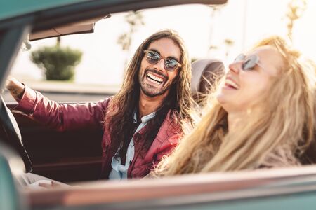 Happy young couple doing road trip in tropical city - Travel people having fun driving in trendy convertible car discovering new places - Relationship and youth vacation lifestyle conceptの写真素材