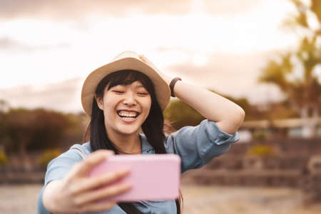 Happy Asian girl taking selfie with mobile smartphone during vacation - Travel Chinese woman having...