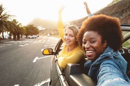 Young happy women taking selfie doing road trip - Travel girls having fun driving in trendy...