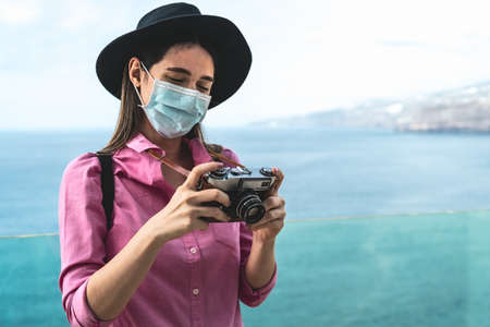 Young travel woman photographing with old vintage camera - Happy girl wearing face surgical mask exploring new touristic destinations - Health care and tourism conceptの写真素材