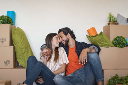 Happy young couple moving in new home first time - Man and woman having fun unpacking carton box in new property house - Change apartment day and people lifestyle relationship conceptの写真素材