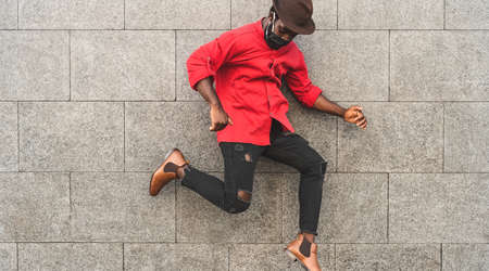African fashion man dancing and having fun outdoor wearing protective face mask to avoid corona virus spread - Safety fun and youth millennial people lifestyle conceptの写真素材