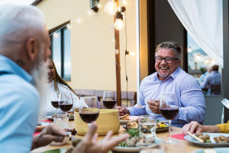 Happy senior friends having fun dining together on house patio - Food and elderly people lifestyle...