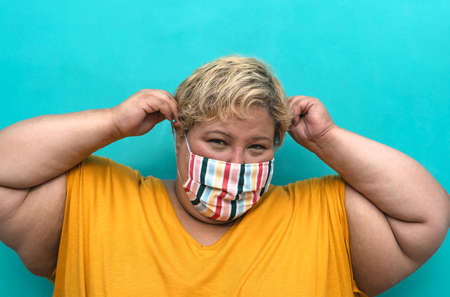 Happy plus size woman wearing face mask portrait - Curvy overweight model having fun posing in front...
