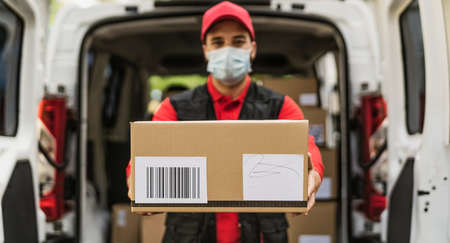 Delivery man wearing face protective mask to avoid corona virus spread - Young express courier...