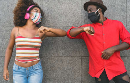 African friends wearing face protective mask while doing new social distance greetings bumping...