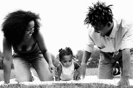 Happy African family having fun together in public park - Black father and mother enjoying time with their daughterの写真素材