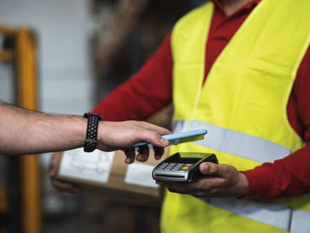 Close up customer making a payment with mobile smartphone inside warehouse - Logistic and smart pay conceptの写真素材