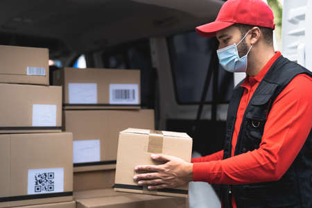 Delivery man wearing face protective mask to avoid  virus spread - Young express courier working...