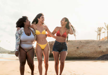 Happy multiracial females with different body size having fun on the beach during summer holidaysの写真素材