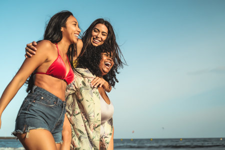 Happy multiracial girls with different body size having fun on the beach during summer holidaysの写真素材
