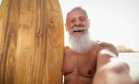 Fitness senior man taking selfie while having fun surfing on sunny day - Elderly people lifestyle...