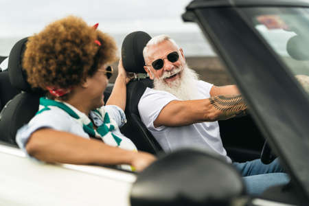 Happy senior couple having fun driving on new convertible car - Mature people enjoying time together...