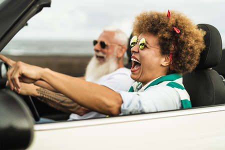 Happy senior couple having fun driving on new convertible car - Mature people enjoying time together during road trip tour vacation - Elderly lifestyle and travel culture transportation conceptの写真素材