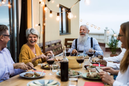 Happy senior friends having fun dining together on house patio - Elderly lifestyle people and food conceptの写真素材