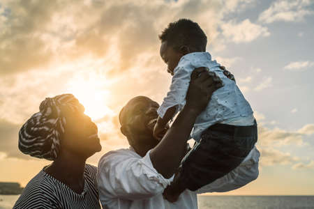 Happy African family having fun on the beach during summer holidays - Parents love concept