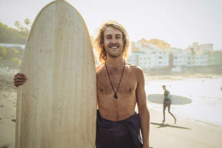 Young surfer having fun enjoying a surf day at sunset time - Extreme sport lifestyle people concept