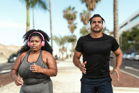 Personal trainer doing running exercises with afro curvy woman - Sporty people lifestyle concept