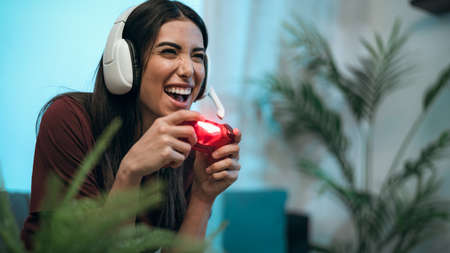 Young woman playing online video games at home - Youth people addicted to new technology gaming...