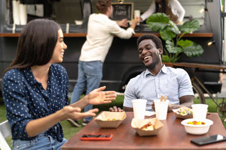 Happy multiracial friends having fun eating in a street food truck marketの写真素材