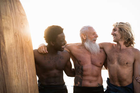 Happy fit surfers with different age and race having fun surfing together at sunset time - Extreme...