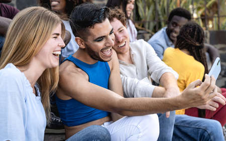Young multiracial group of friends taking selfie with mobile smartphone sitting on stairs - Youth millennial lifestyle conceptの写真素材
