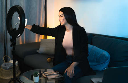 Young woman vlogging online with smartphone cam and ring led from home - Youth people with social media and smart working conceptの写真素材