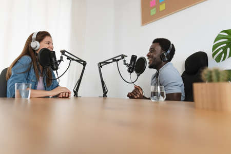 Multiracial people recording a podcast using microphone and headphones from home studioの写真素材