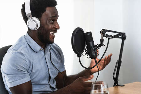 African man recording a podcast using microphone and headphones from his home studioの写真素材