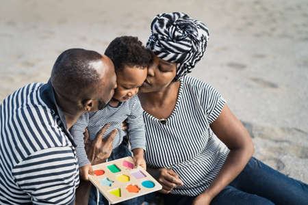 Happy African family having fun on the beach during summer holidays - Parents love concept