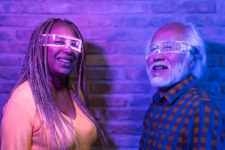 Happy senior friends having fun with futuristic augmented reality glasses - Metaverse concept